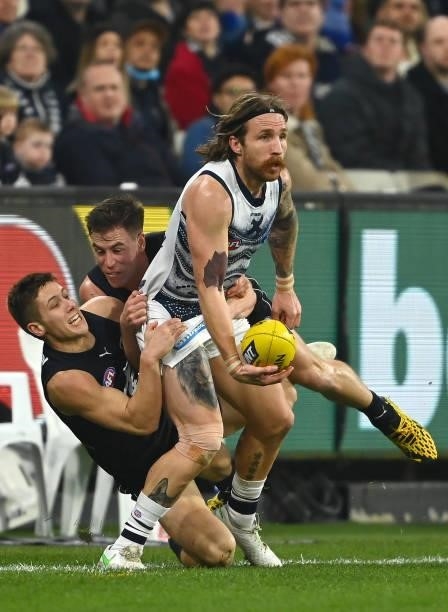 Zach Tuohy of the Cats handballs whilst being tackled by Lachie Fogarty and Matthew Owies of the Blues during the round 17 AFL match between Carlton...