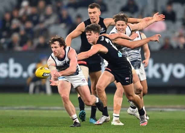Jed Bews of the Cats handballs whilst being tackled by Paddy Dow of the Blues during the round 17 AFL match between Carlton Blues and Geelong Cats at...