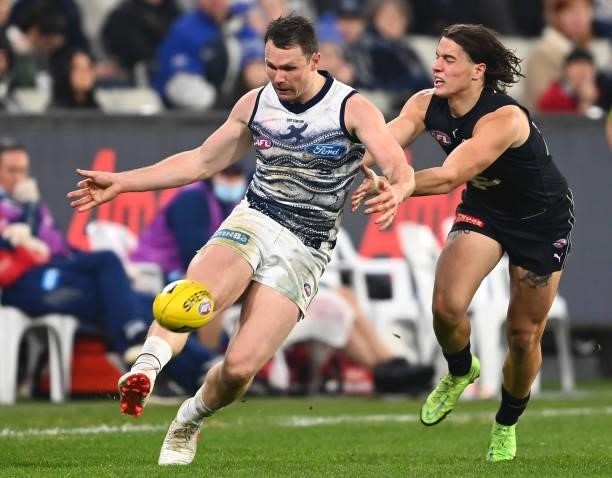 Patrick Dangerfield of the Cats kicks whilst being tackled by Liam Stocker of the Blues during the round 17 AFL match between Carlton Blues and...