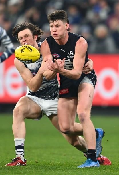 Sam Walsh of the Blues handballs whilst being tackled by Max Holmes of the Cats during the round 17 AFL match between Carlton Blues and Geelong Cats...