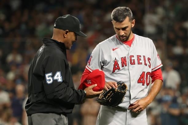 Steve Cishek of the Los Angeles Angels is checked by umpire CB Bucknor for illegal substances after being pulled from the game during the seventh...
