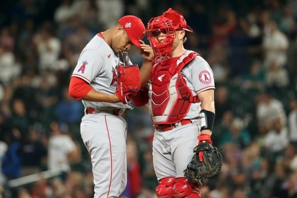 Jose Quintana and Max Stassi of the Los Angeles Angels have a conversation after issuing a walk to J.P. Crawford of the Seattle Mariners during the...