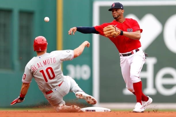 Xander Bogaerts of the Boston Red Sox turns a double play over J.T. Realmuto of the Philadelphia Phillies during the first inning at Fenway Park on...