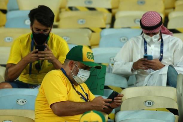 Fans look at their phones as they wait for the start of the match prior to the final of Copa America Brazil 2021 between Brazil and Argentina at...