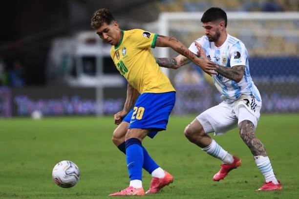Roberto Firmino of Brazil fights for the ball with Rodrigo De Paul of Argentina during the final of Copa America Brazil 2021 between Brazil and...