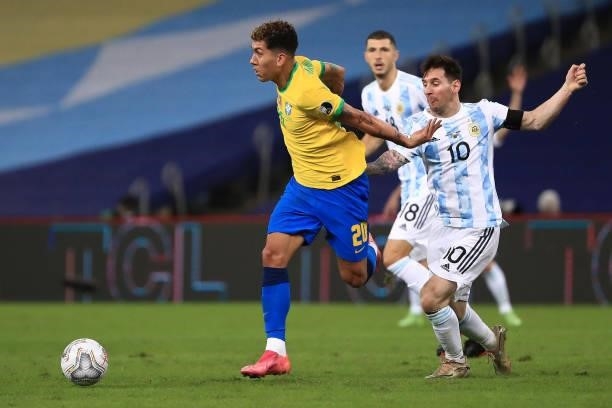 Roberto Firmino of Brazil fights for the ball with Lionel Messi of Argentina during the final of Copa America Brazil 2021 between Brazil and...