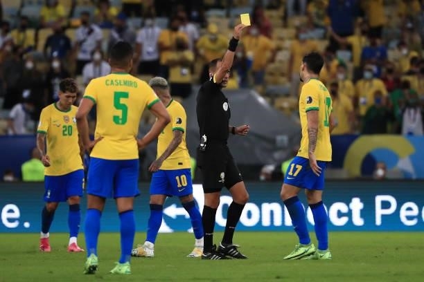 Referee Esteban Ostojich shows a yellow card to Lucas Paqueta of Brazil during the final of Copa America Brazil 2021 between Brazil and Argentina at...