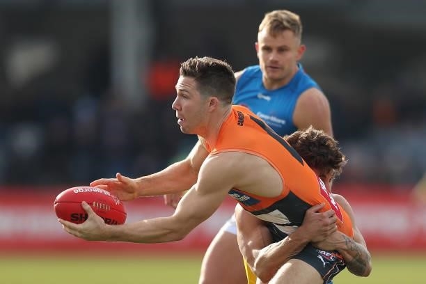 Toby Greene of the Giants handballs as he is tackled during the round 17 AFL match between Greater Western Sydney Giants and Gold Coast Suns at Mars...