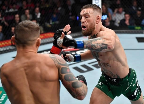 Conor McGregor of Ireland punches Dustin Poirier in their welterweight fight during the UFC 264 event at T-Mobile Arena on July 10, 2021 in Las...