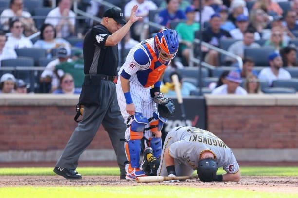 Catcher Tomas Nido of the New York Mets looks down at John Nogowski of the Pittsburgh Pirates who injured himself while batting during game one of a...