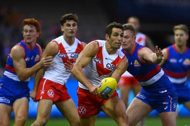 Josh P. Kennedy of the Swans handballs whilst being tackled by Alex Keath of the Bulldogs during the round 17 AFL match between Western Bulldogs and...