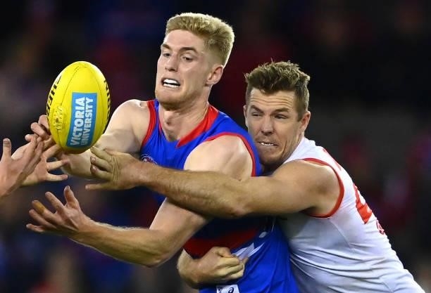 Tim English of the Bulldogs handballs whilst being tackled by Luke Parker of the Swans during the round 17 AFL match between Western Bulldogs and...