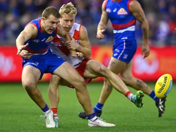 Jackson Macrae of the Bulldogs handballs whilst being tackled by Isaac Heeney of the Swans during the round 17 AFL match between Western Bulldogs and...