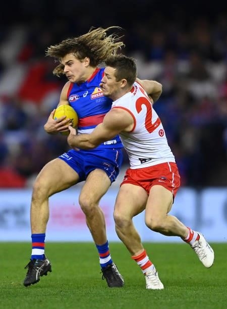 Bailey Smith of the Bulldogs is tackled by Luke Parker of the Swans during the round 17 AFL match between Western Bulldogs and Sydney Swans at Marvel...