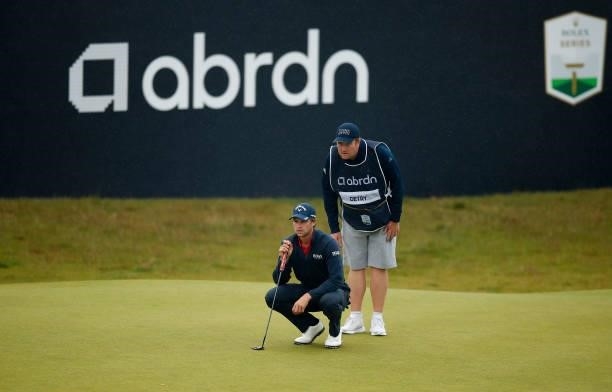 Thomas Detry of Belgium lines up his putt with caddie Michael Burrow on the 18th green during Day Four of the abrdn Scottish Open at The Renaissance...
