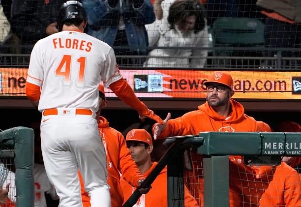 Wilmer Flores of the San Francisco Giants is congratulated by manager Gabe Kapler after Flores hit a solo home run against the Washington Nationals...