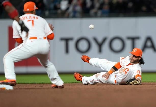 Brandon Crawford of the San Francisco Giants starts the double-play from the ground using his glove to toss the ball to Donovan Solano against the...