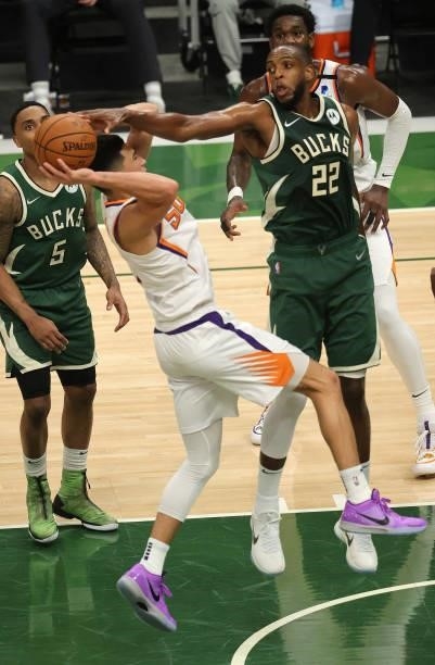 Khris Middleton of the Milwaukee Bucks blocks a shot by Devin Booker of the Phoenix Suns as he drives into the lane during the first half in Game...