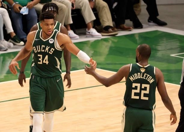 Giannis Antetokounmpo of the Milwaukee Bucks and teammate Khris Middleton give each other a high five during the first half in Game Three of the NBA...