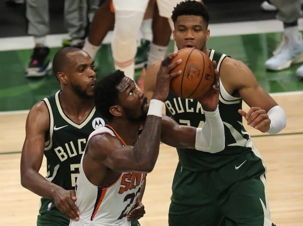 Deandre Ayton of the Phoenix Suns goes is defended by Khris Middleton and Giannis Antetokounmpo of the Milwaukee Bucks during the first half in Game...