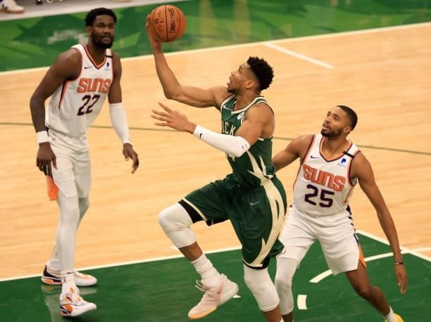 Giannis Antetokounmpo of the Milwaukee Bucks drives past Mikal Bridges of the Phoenix Suns for a layup during the second half in Game Three of the...