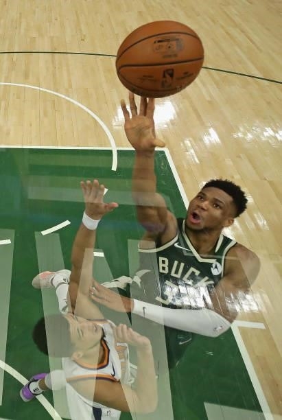 Giannis Antetokounmpo of the Milwaukee Bucks shoots over Devin Booker of the Phoenix Suns at Fiserv Forum on July 11, 2021 in Milwaukee, Wisconsin.