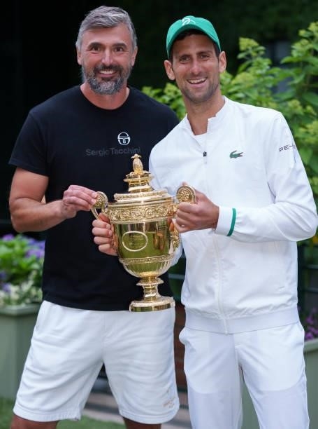 Novak Djokovic of Serbia and his coach Goran Ivanisevic of Croatia hold the Gentlemen's Singles Trophy on the players lawn during Day Thirteen of The...