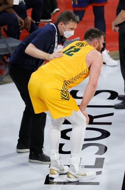 Trainer checks on Aron Baynes of the Australia Boomers after he appeared to hurt his knee during an exhibition game against the United States at...