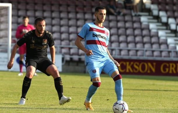 Nathan Holland of West Ham United plays the ball watched by Michael Harriman of Northampton Town during the Pre-Season Friendly match between...