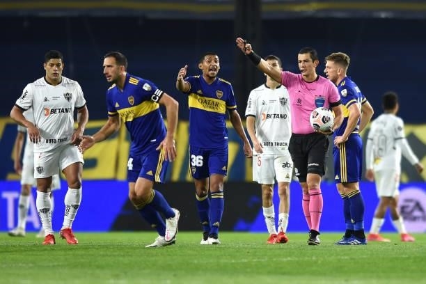 Referee Andres Rojo gestures as Cristian Medina of Boca Juniors reacts during a round of sixteen match between Boca Juniors and Atletico Mineiro as...