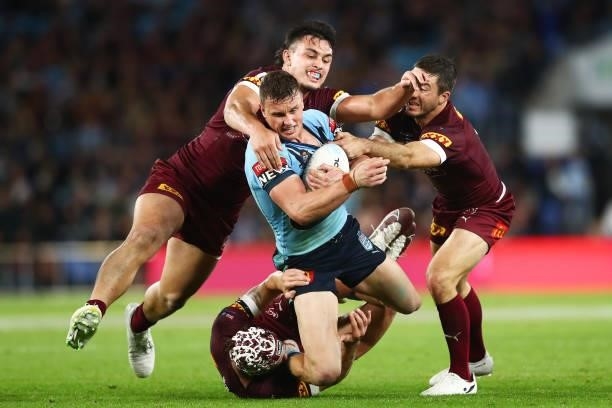 Jack Wighton of the Blues is tackled by Tino Fa'asuamaleaui and Ben Hunt of the Maroons during game three of the 2021 State of Origin Series between...