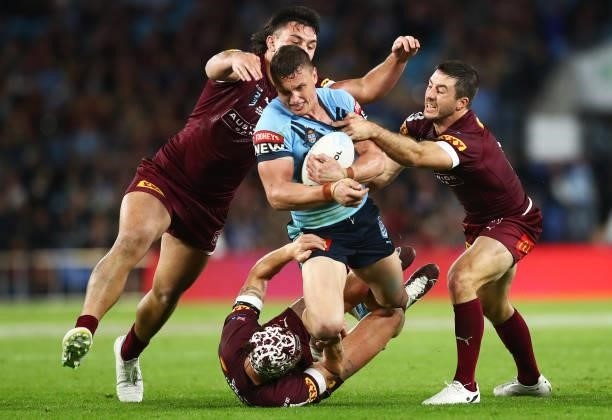 Jack Wighton of the Blues is tackled by Tino Fa'asuamaleaui and Ben Hunt of the Maroons during game three of the 2021 State of Origin Series between...