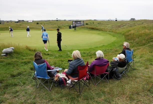Spectators sit near the green as players putt during a practice round for The 149th Open at Royal St George’s Golf Club on July 14, 2021 in Sandwich,...