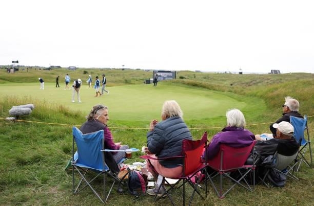 Spectators sit near the green as players putt during a practice round for The 149th Open at Royal St George’s Golf Club on July 14, 2021 in Sandwich,...
