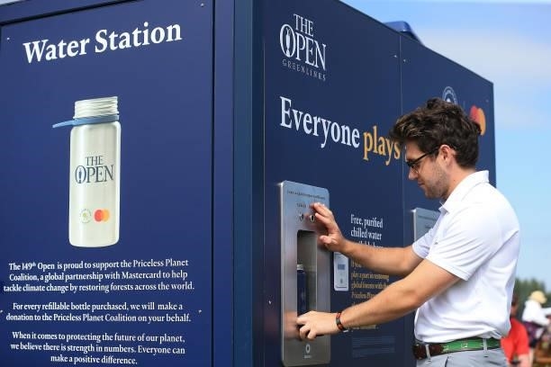 Niall Horan refills a reusable water bottle from a water station as he is interviewed on event sustainability during Day One of The 149th Open at...