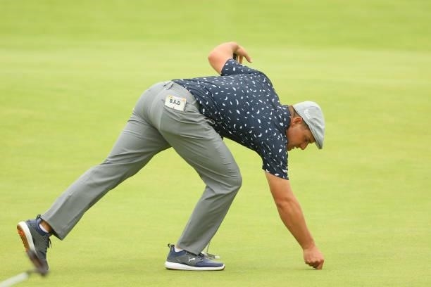 Bryson DeChambeau of the United States places down a green marker on the 18th hole during Day One of The 149th Open at Royal St George’s Golf Club on...