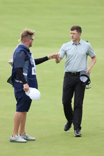 Mackenzie Hughes of Canada fist bumps caddie on the 18th green during Day One of The 149th Open at Royal St George’s Golf Club on July 15, 2021 in...