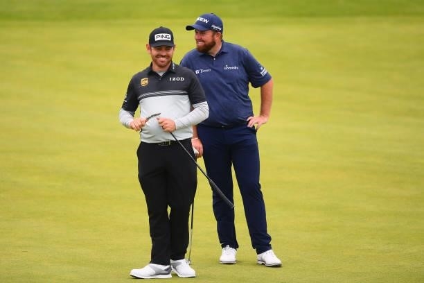 Defending champion Shane Lowry of Ireland and Louis Oosthuizen of South Africa smile on the 18th green during Day One of The 149th Open at Royal St...