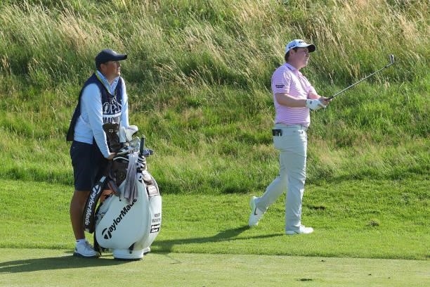 Robert MacIntyre of Scotland watches his second shot on the ninth hole alongside his caddie during Day One of The 149th Open at Royal St George’s...
