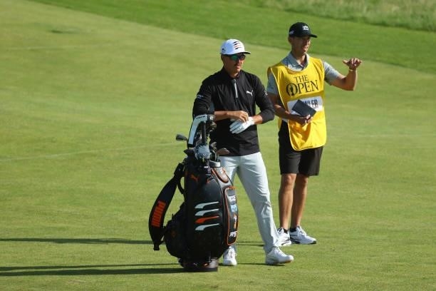 Rickie Fowler of the United States prepares to play his second shot on the ninth hole alongside caddie Joe Skovron during Day One of The 149th Open...