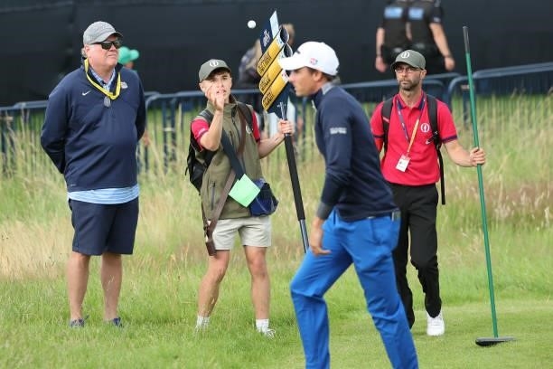 Benjamin Herbert of France throws a ball to a marshal carrying a scoreboard during Day One of The 149th Open at Royal St George’s Golf Club on July...