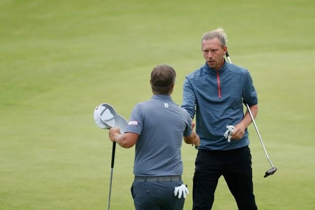 Marcel Siem of Germany shakes hands with Matt Jones of Australia on the 18th green during Day One of The 149th Open at Royal St George’s Golf Club on...