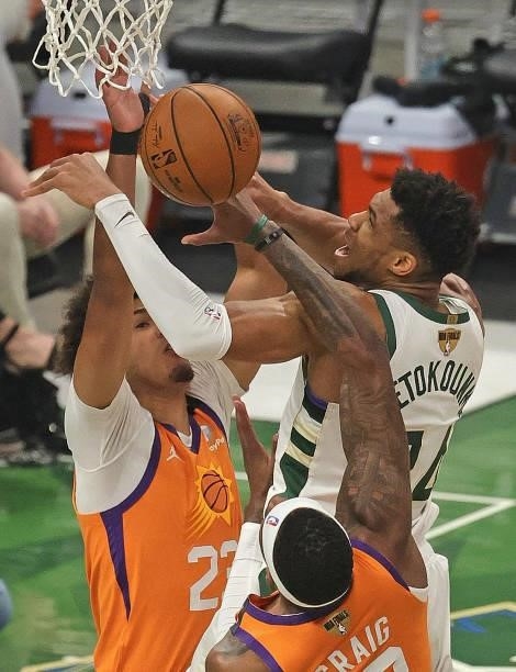 Giannis Antetokounmpo of the Milwaukee Bucks is pressured trying to shoot by Cameron Johnson and Torrey Craig of the Phoenix Suns at Fiserv Forum on...