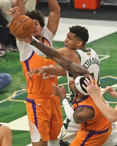 Giannis Antetokounmpo of the Milwaukee Bucks is pressured trying to shoot by Cameron Johnson and Torrey Craig of the Phoenix Suns at Fiserv Forum on...