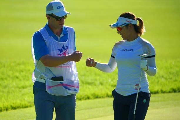 Eri Okayama of Japan fist bumps with her caddie after holing out with the birdie on the 18th green during first round of the GMO Internet Ladies...