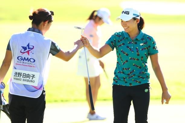 Hinako Shibuno of Japan fist bumps with her caddie after holing out on the 18th green during first round of the GMO Internet Ladies Samantha Thavasa...