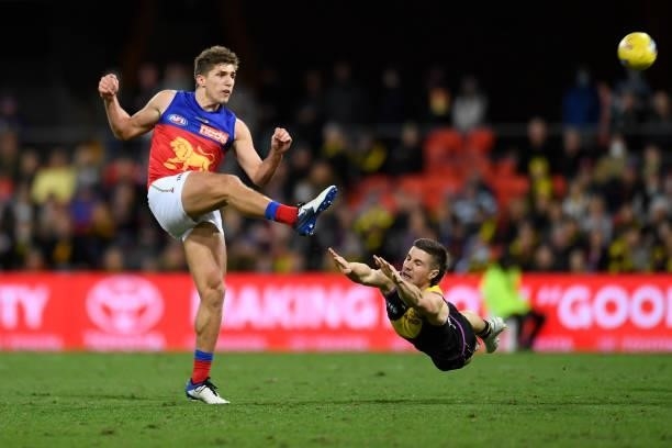 Zac Bailey of the Lions kicks under pressure from Liam Baker of the Tigers during the round 18 AFL match between the Richmond Tigers and the Brisbane...