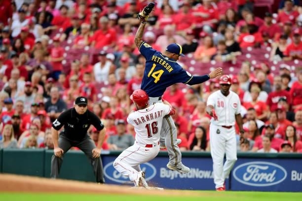 Tucker Barnhart of the Cincinnati Reds collides with Jace Peterson of the Milwaukee Brewers at first base in the first inning during their game at...
