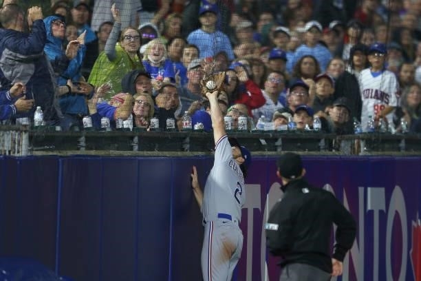 Charlie Culberson of the Texas Rangers reaches to catch a foul ball by Randal Grichuk of the Toronto Blue Jays, but the ball is on the other side of...