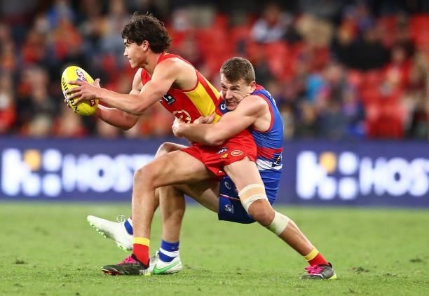 Wil Powell of the Suns is tackled by Jack Macrae of the Bulldogs during the round 18 AFL match between Gold Coast Suns and Western Bulldogs at...